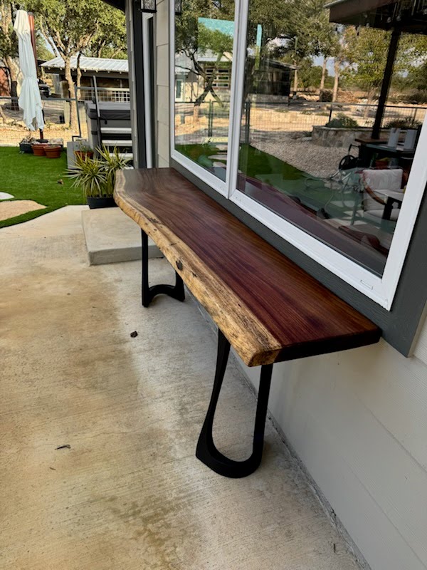 Live edge walnut console table with sculpted steel base on outdoor patio