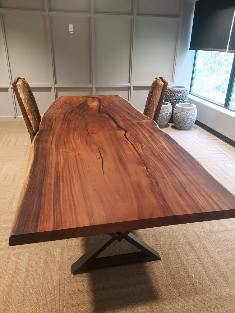 Large live edge conference table with X-shaped steel base in a paneled office